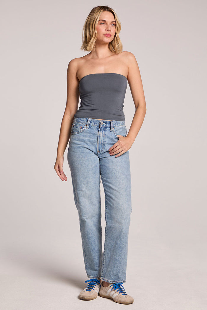 A full body view of a woman wearing the Chaser Future Grey Pearl Tube Top and jeans on a neutral background