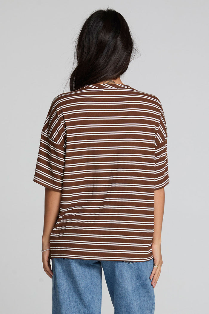 Back view of a woman wearing the Chaser Peri Nutty Brown Stripe Tee and jeans on a neutral background