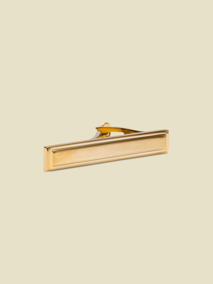 Brushed gold picture-frame tie bar on cream background