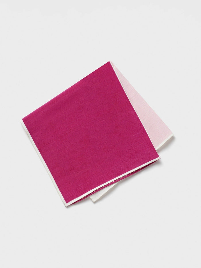 Folded pink pocket square with white border on white background