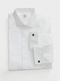 White pleated tuxedo shirt with black studs, folded flat, on light grey background