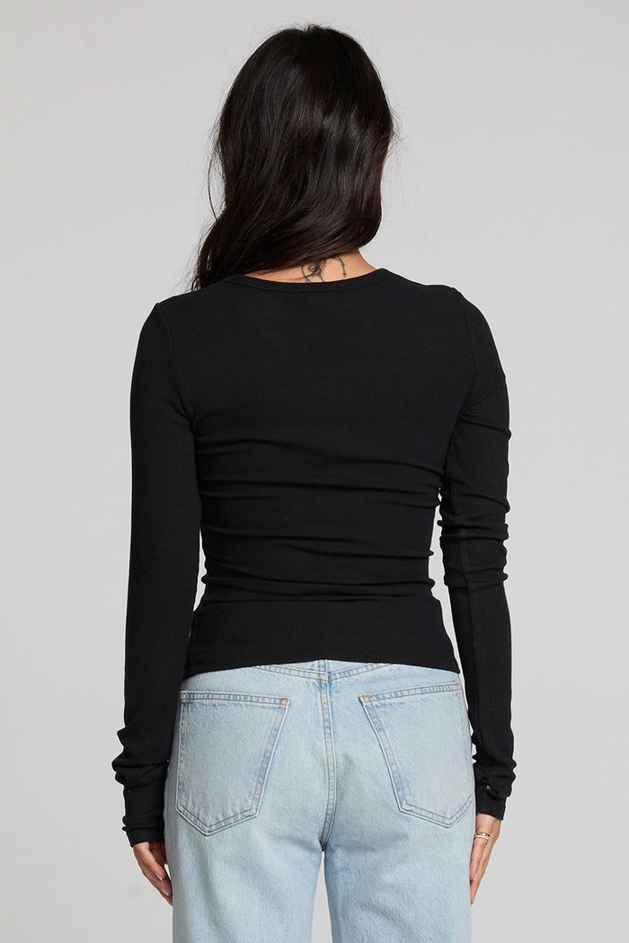 Back view of a woman wearing the Chaser Porta Black Long Sleeve on a neutral background with blue jeans