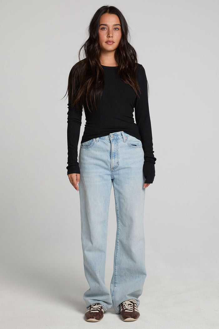 Full body view of a woman wearing the Chaser Porta Black Long Sleeve on a neutral background with blue jeans and sneakers