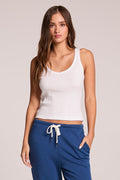 Front view of a woman wearing the Chaser   Prescot White Tank Top and blue pants on a neutral background