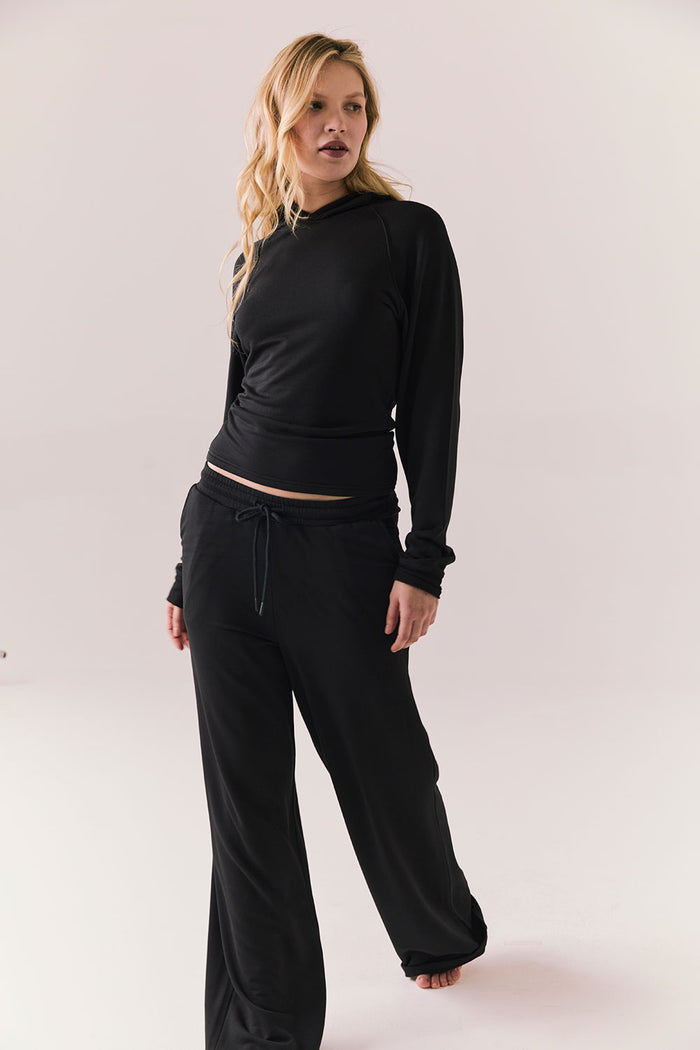 Full body view of model in black Providence hoodie styled with matching black lounge pants.