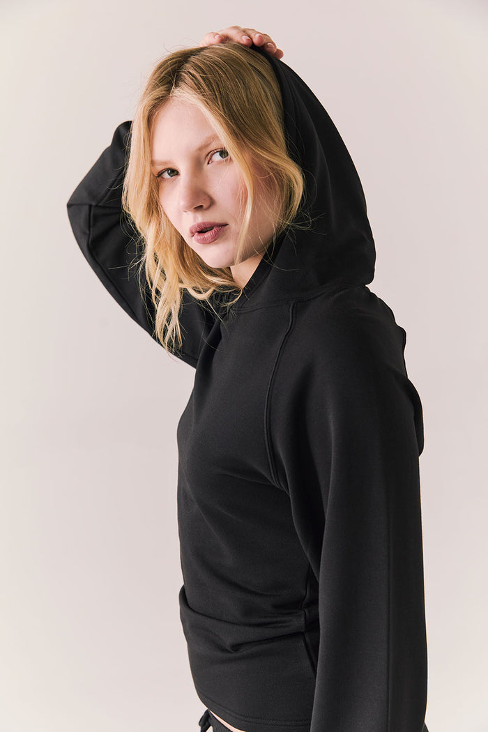 Side angle of black hoodie showing relaxed shoulder and clean drape.