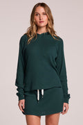 Front view of a woman wearing the Chaser  Providence Pine Green Hoodie and matching skort on a neutral background