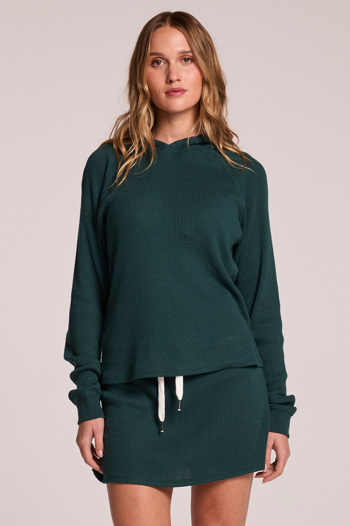 Front view of a woman wearing the Chaser  Providence Pine Green Hoodie and matching skort on a neutral background