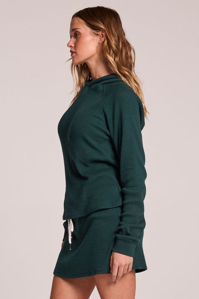 Side view of a woman wearing the Chaser  Providence Pine Green Hoodie on a neutral background with hands at her sides