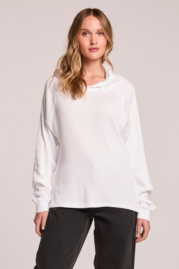 Front view of a woman wearing the Chaser   Providence White Hoodie and black pants on a neutral background