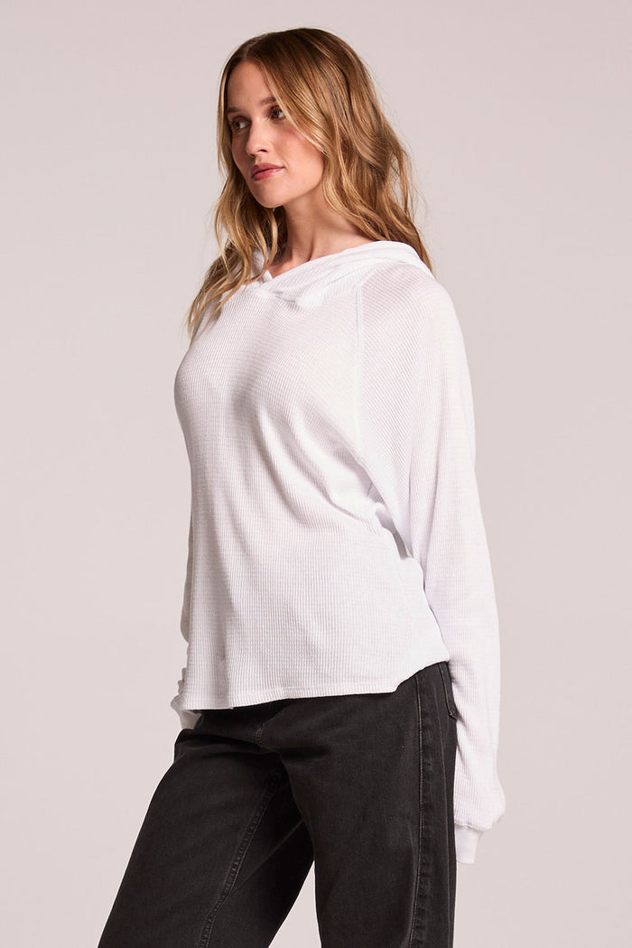 Side angle view of a woman wearing the Chaser   Providence White Hoodie on a neutral background with hands behind her back