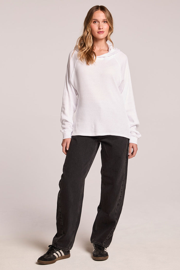 Front view of a woman wearing the Chaser   Providence White Hoodie and black shoes on a neutral background