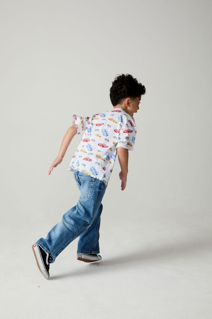 Front view of a boy wearing the Chaser Race Day Boys Tee on a neutral background with bluejeans in a racing pose