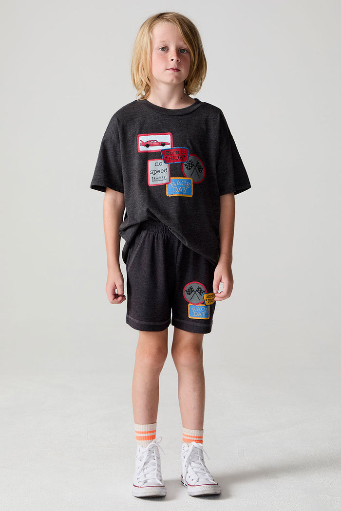 Full body front view of a boy wearing the Chaser Race Patches Shorts on a neutral background