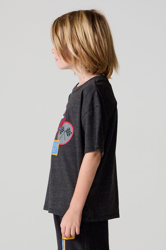 Side view of a boy wearing the Chaser Race Patches Tee on a neutral background