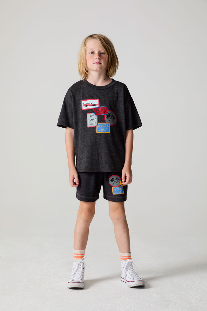 Full body front view of a boy wearing the Chaser Race Patches Tee on a neutral background