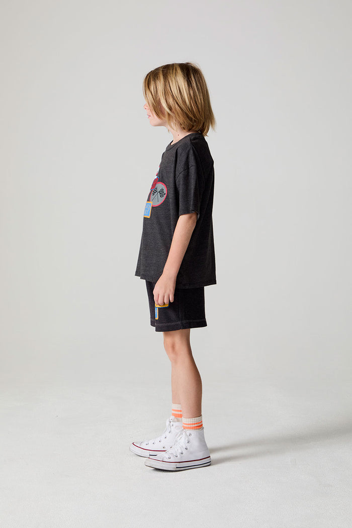 Full body side view of a boy wearing the Chaser Race Patches Tee on a neutral background