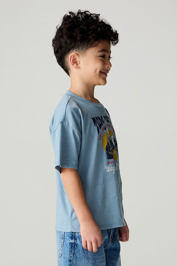 Side view of a boy wearing the Chaser Racers Boys Tee on a neutral background with jeans and arms at sides