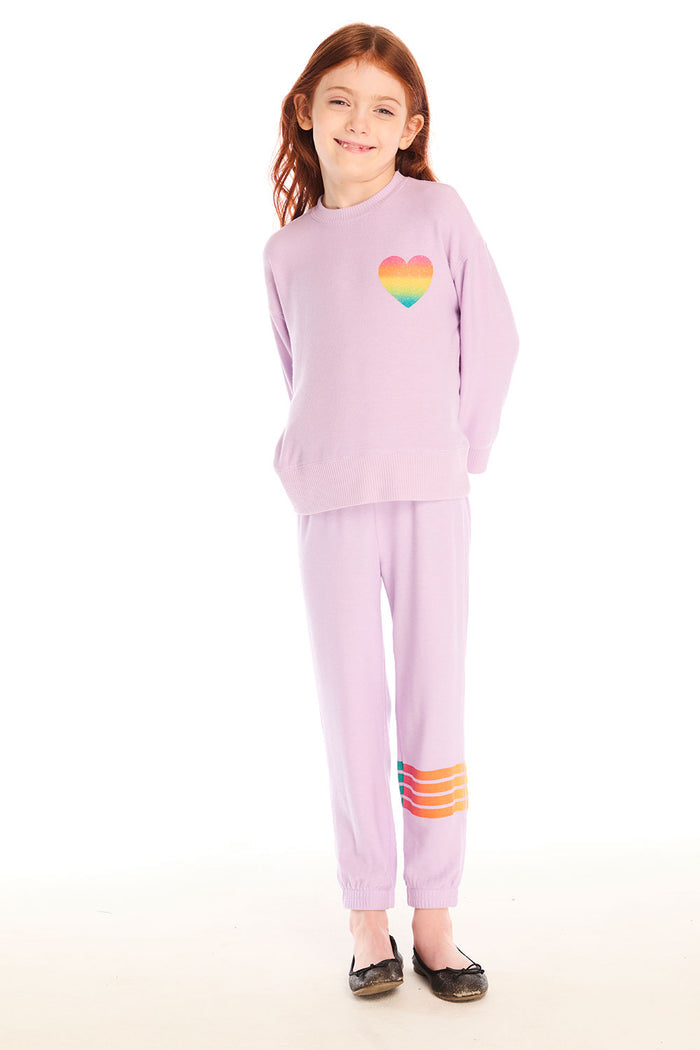 Full body view of girl wearing Chaser’s pink Rainbow Glitter Pants with rainbow heart design and matching pullover on a white background