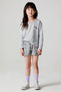 Full body front view of a girl wearing the Chaser  Rainbow Morning Allover Shorts on a neutral background