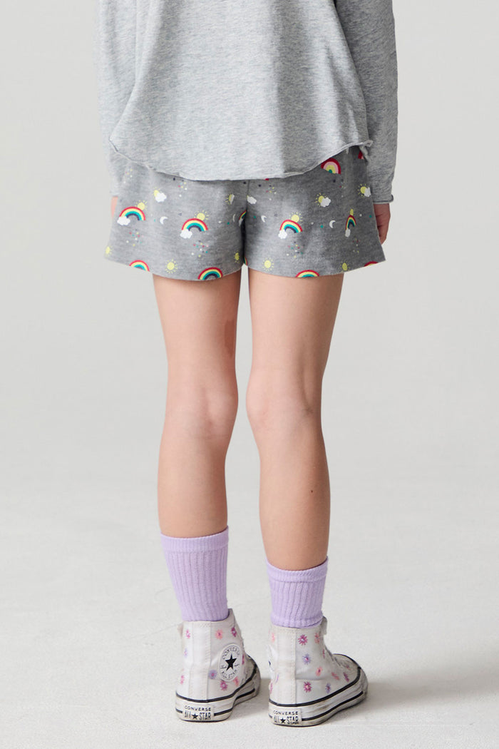 Back view of a girl wearing the Chaser  Rainbow Morning Allover Shorts on a neutral background