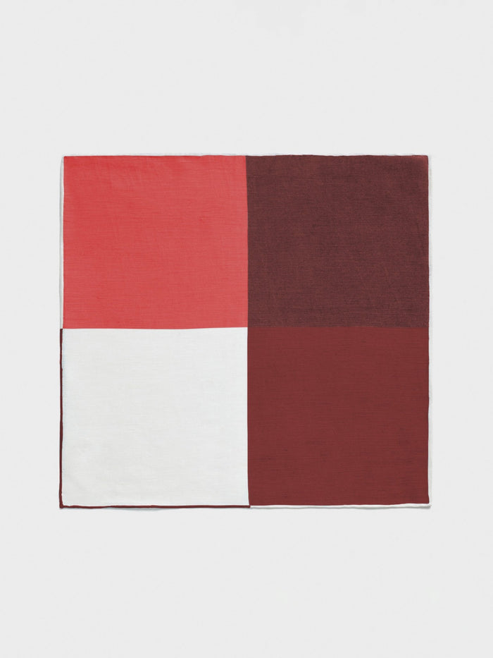 Pocket square with four solid color-block quadrants: coral, brown, white, and deep red, laid flat.