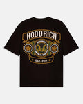 A black short-sleeve t-shirt with a large graphic print on the front. The graphic features the brand name 'HOODRICH' in white letters inside a gold-bordered arch, with circular medallions containing gold stars and a central gold double-horns emblem, and 'EST 2014.