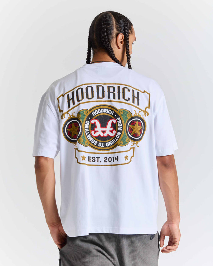 A man shown from the back wearing a white HOODRICH t-shirt with a large graphic print on the back, paired with gray sweatpants against a light gray studio background.