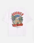 A white short-sleeve t-shirt shown from the back, featuring a large graphic print with the brand name 'HOODRICH' in red arched letters above a retro illustration of a building and palm trees, and 'Worldwide' in red script below.