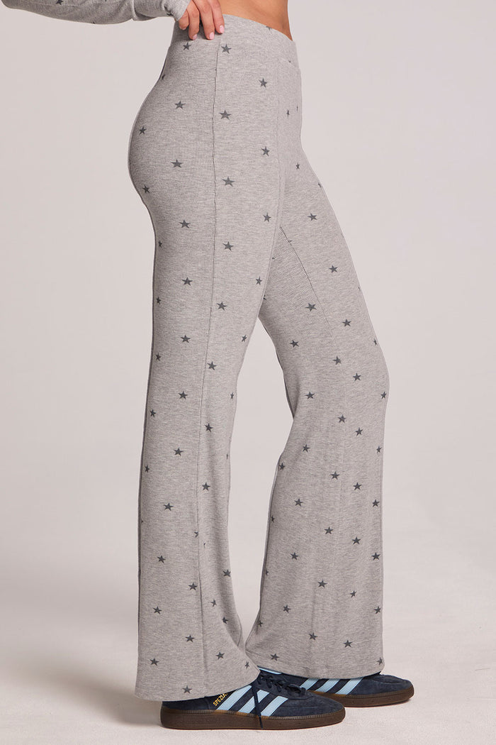 Side view of a woman wearing the Chaser Rhose Light Heather Grey Pants on a neutral background with arms on hips