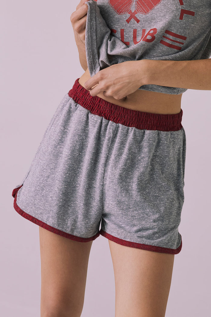 Close-up of the Ringer Shorts in Heather Grey with Crimson trim highlighting the textured waistband and curved hem
