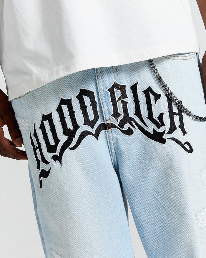 Light blue jeans with 'Hoodrich' text design worn by a person.