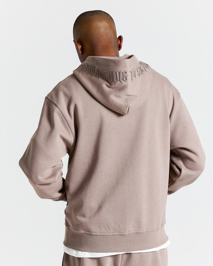 Person wearing a beige hoodie with text on the back against a light gray background