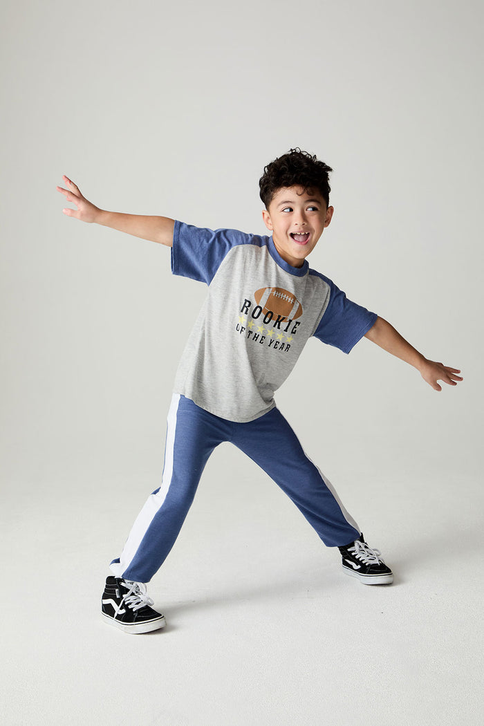 A full body front view of a boy wearing the Chaser Rookie Boys Tee on a neutral background doing a wild pose