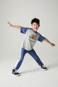 A full body front view of a boy wearing the Chaser Rookie Boys Tee on a neutral background doing a wild pose