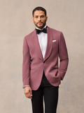 Man in dusty rose shawl collar tuxedo jacket and black trousers with black bow tie, close-up front view