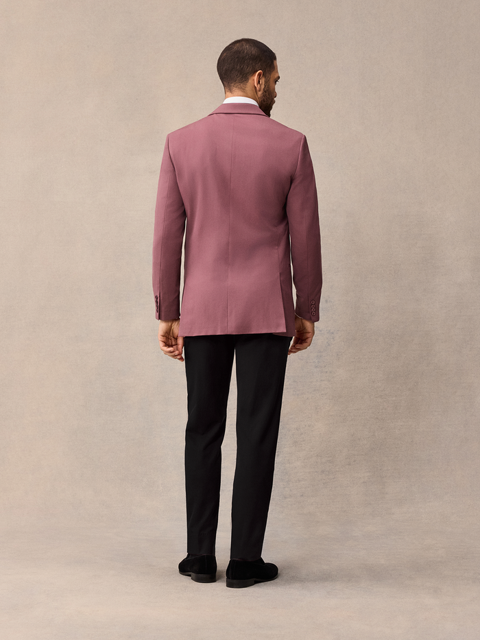Back view of man in dusty rose shawl collar tuxedo jacket and black trousers