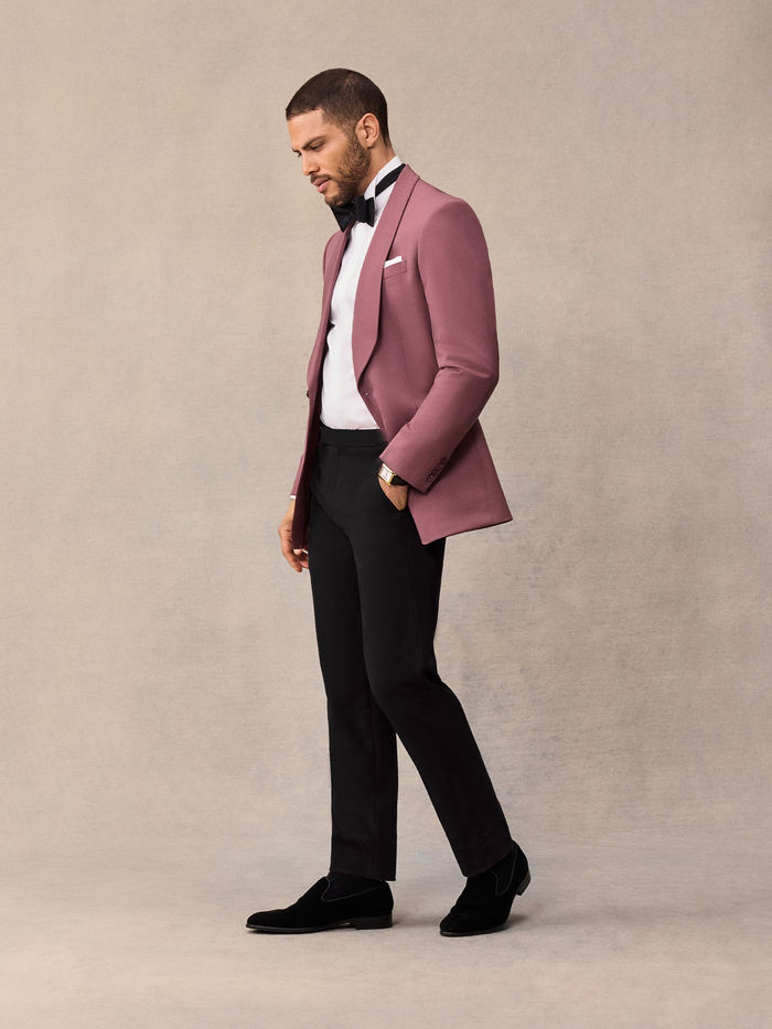 Man in dusty rose shawl collar tuxedo jacket and black trousers, side profile, looking down