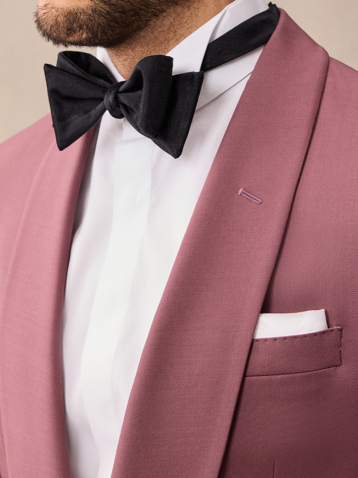 Close-up of black bow tie and dusty rose satin shawl lapel with white pocket square