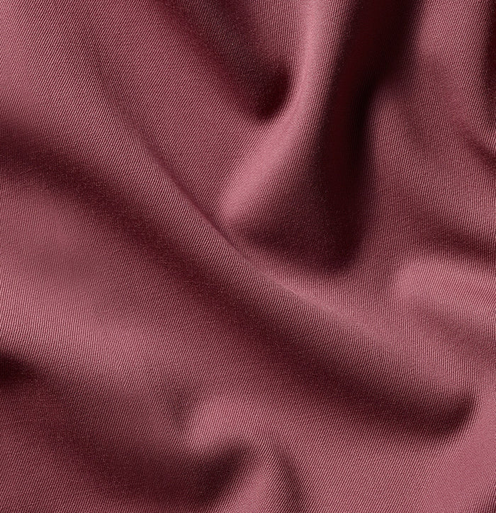 Close-up of dusty rose satin fabric with soft draped folds