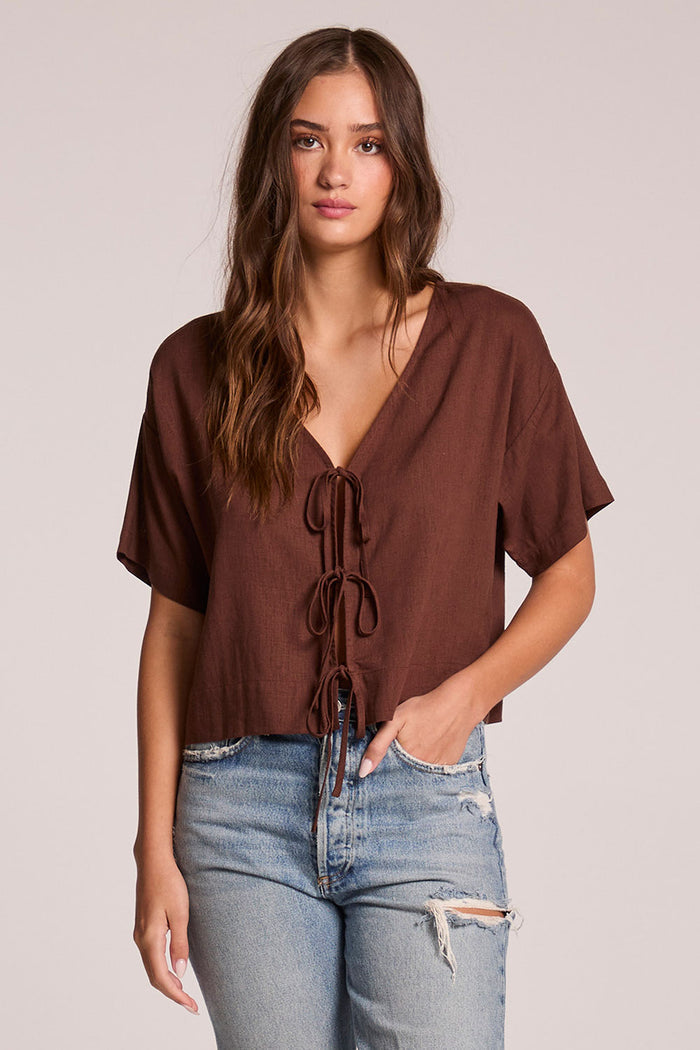 Front view of a woman wearing the Chaser Roselie Kahlua Blouse and jeans on a neutral background with one hand in her pocket