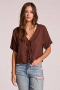 Front view of a woman wearing the Chaser Roselie Kahlua Blouse and jeans on a neutral background with one hand in her pocket