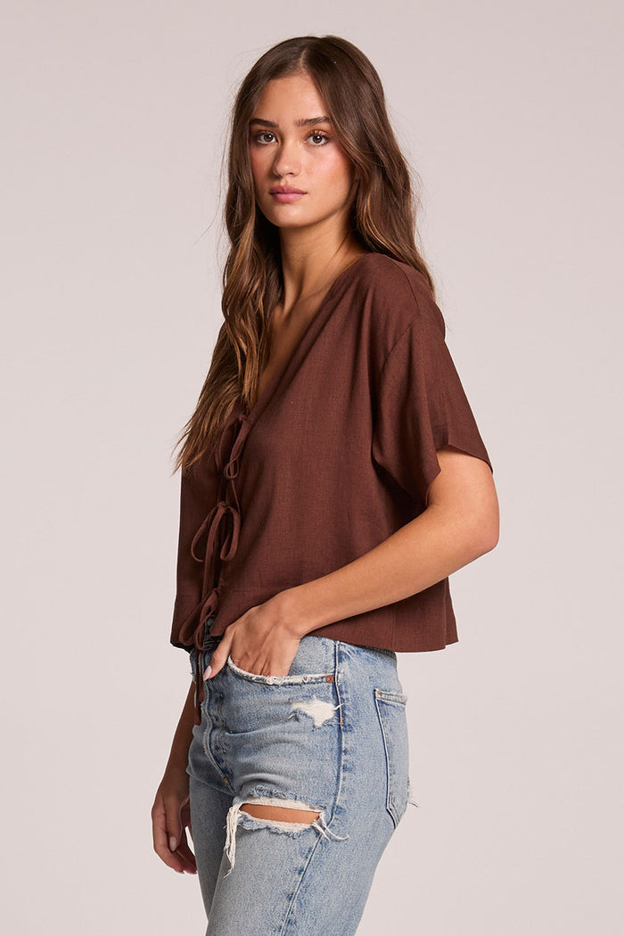 Side angle view of a woman wearing the Chaser Roselie Kahlua Blouse and jeans on a neutral background