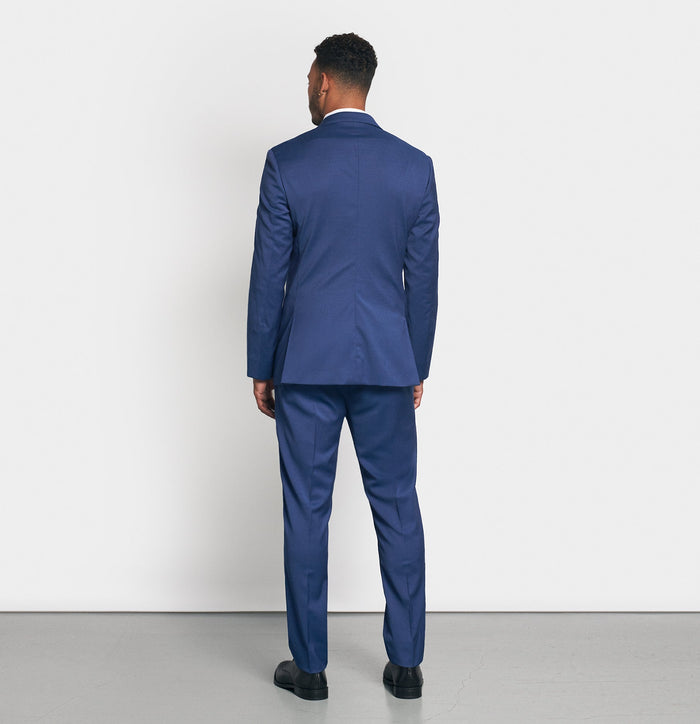 Back view of man in royal blue suit on light grey background