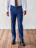 Man in royal blue suit pants, white shirt, and brown tie, front view on wood floor