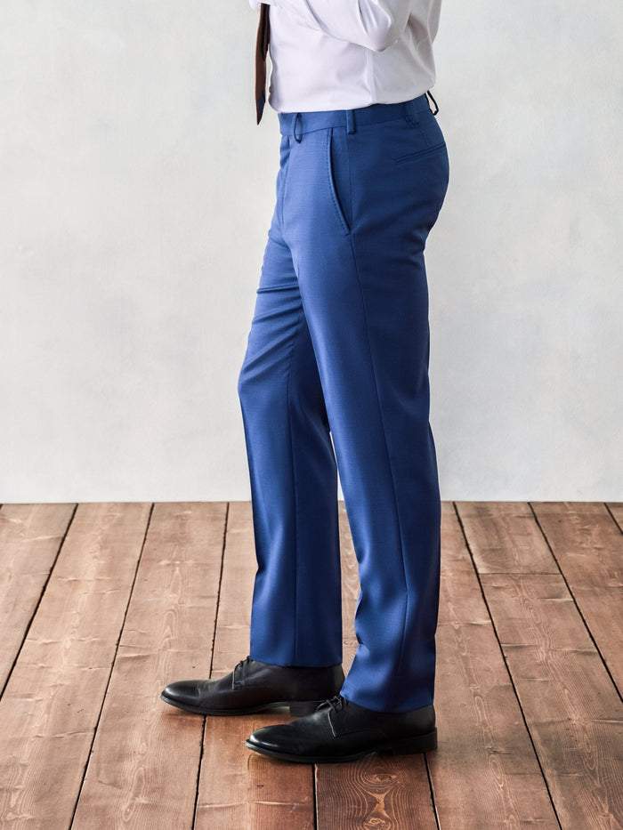 Close-up of man in royal blue suit trousers, side profile, on wood floor