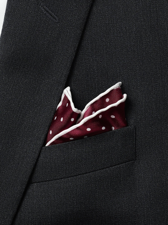 Ruby polka-dot pocket square puffed in a charcoal suit jacket's breast pocket.