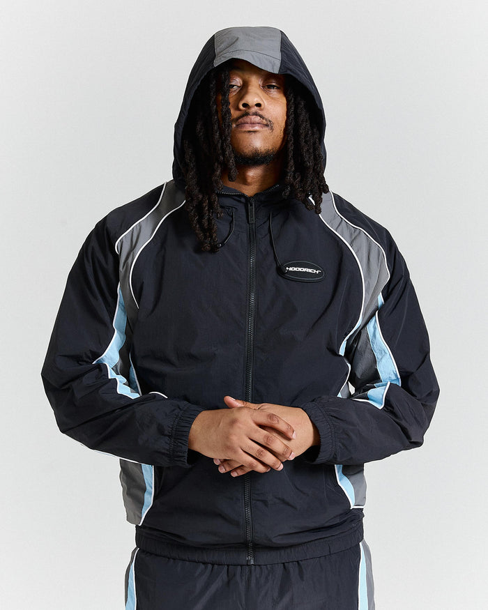 Person wearing a black and gray jacket with a hood on a light gray background