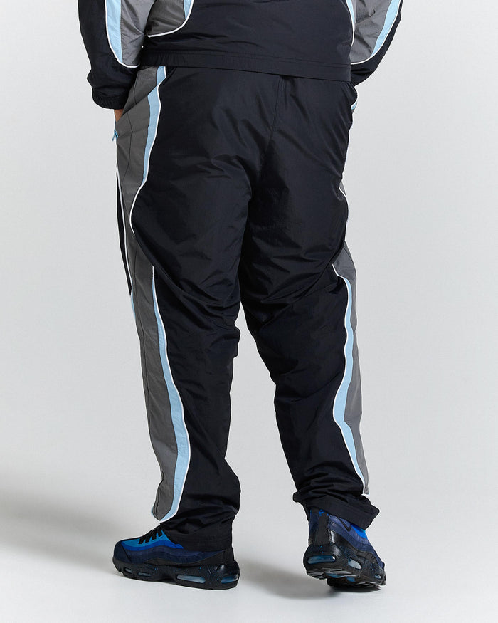 Person wearing black tracksuit with blue stripes on a white background