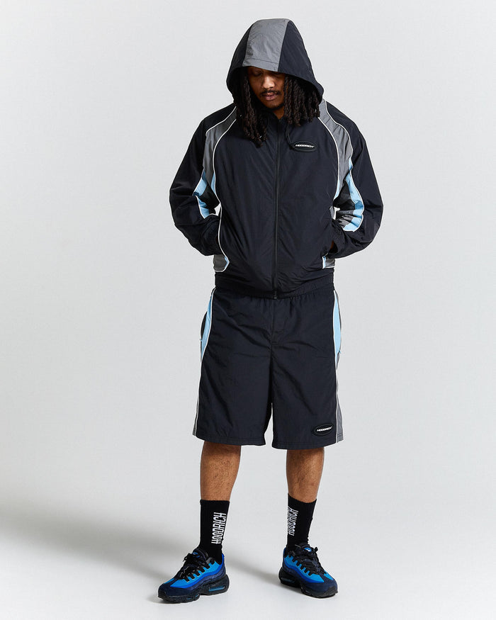 Person wearing a black and grey jacket with blue accents on a white background
